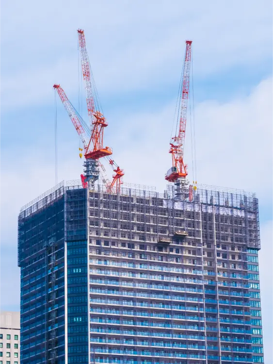 An apartment building under construction with two orange cranes as part of the build-then-sell concept in Malaysia.